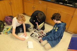 Juniors Nikolai Mather and Graham Cleven and sophomore James Cahoon work on the Robotics Club's robot, Rovo. Becca Heilman/The Omniscient